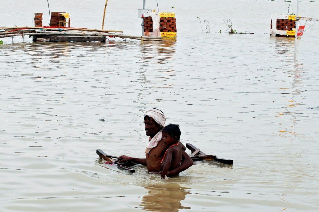 Hindu carrega seu filho no rio Ganges, após fortes chuvas provocarem inundações na região de Allahabad, na Índia - 08/08/2016