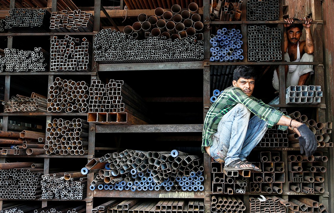 Trabalhadores aguardam para carregar tubos de metal, em uma loja de Mumbai, na Índia - 11/08/2016