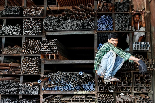 Trabalhadores aguardam para carregar tubos de metal, em uma loja de Mumbai, na Índia - 11/08/2016