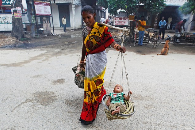 Mulher carrega seu filho em um cesto, na cidade indiana de Allahabad - 11/08/2016
