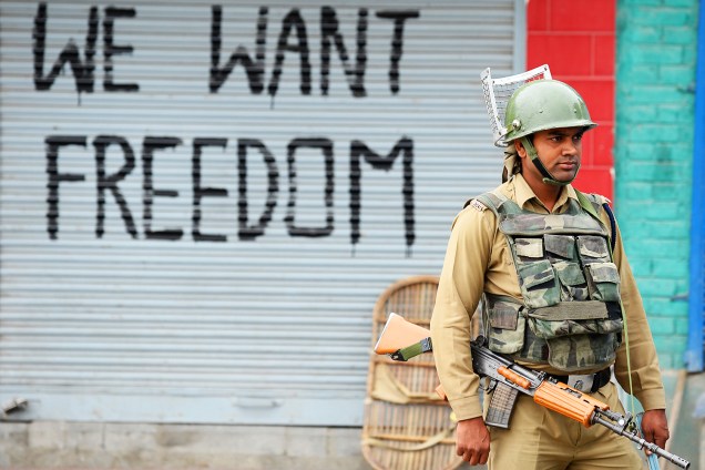 Paramilitar realiza patrulha após toque de recolher na cidade de Srinagar, na região da Caxemira. Atrás, é vista a frase 'Nós queremos liberdade' - 26/08/2016