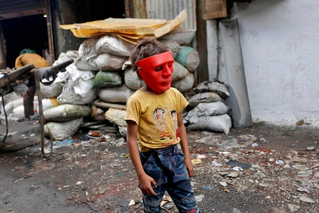 Garoto usa máscara de plástico, em uma área industrial de Mumbai, na Índia - 03/08/2016