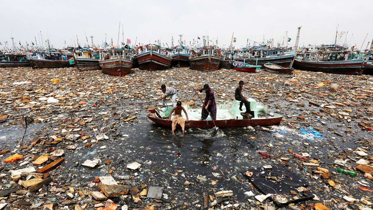 Garotos a bordo de um barco abandonado coletam materiais recicláveis, próximos a barcos de pesca no porto de Karachi, no Paquistão - 17/08/2016