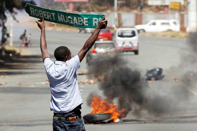 Homem carrega placa de estrada durante confronto com a polícia, em protesto do partido de oposição na cidade de Harare, no Zimbábue - 26/08/2016