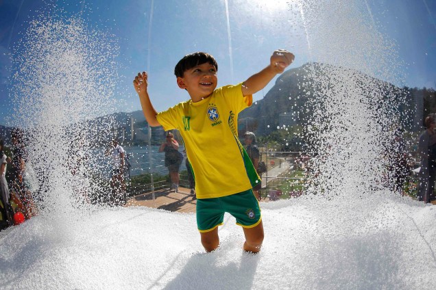 Garoto brinca em uma fonte em frente às instalações da Suiça, na Vila Olímpica - 01/08/2016