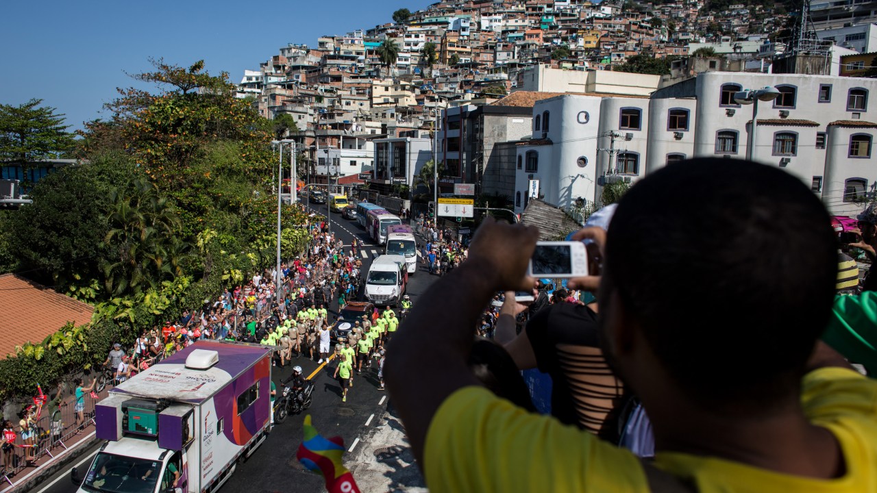 Moradores da favela do Vidigal assistem ao revezamento da tocha no Rio de Janeiro, a caminho do estádio do Maracanã