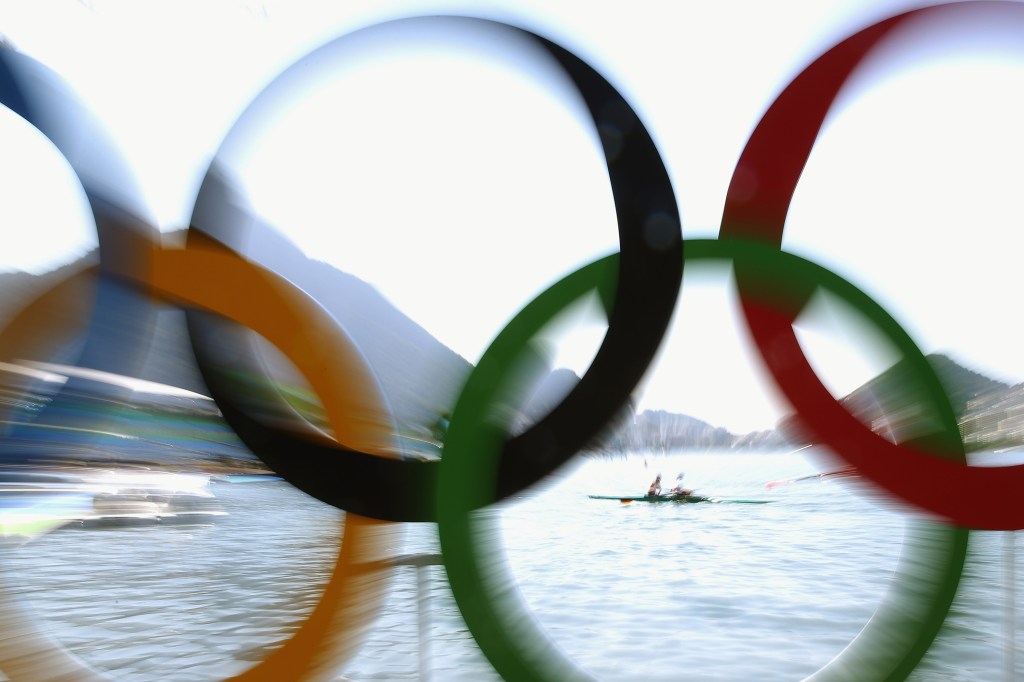 Atletas de remo são fotografados por trás dos arcos olímpicos, no Rio de Janeiro