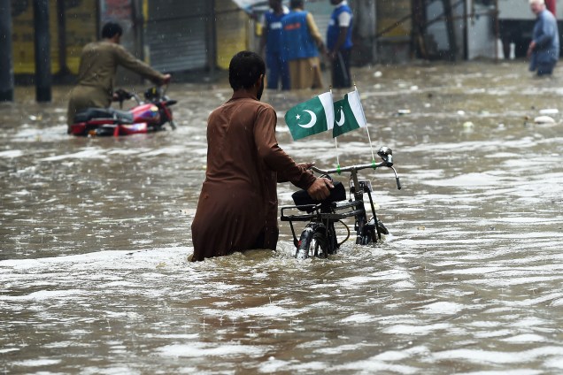 Homem atravessa a rua inundada após forte chuva das monções de verão que atingiram a cidade de Lahore, no Paquistão - 29/08/2016