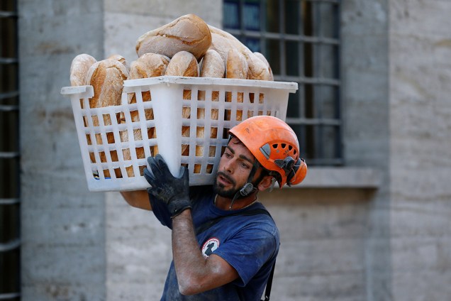 Homem carrega cesta de pães para distribuir às famílias desalojadas pelo terremoto que atingiu a cidade de Amatrice, na Itália - 24/08/2016