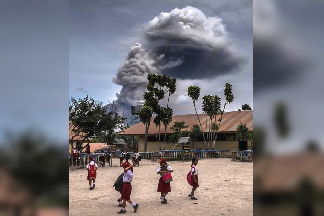 Estudantes brincam em uma escola enquanto o Monte Sinabung expele cinzas durante um erupção em Karo, província de Sumatra Setentrional, na Indonésia - 30/08/2016