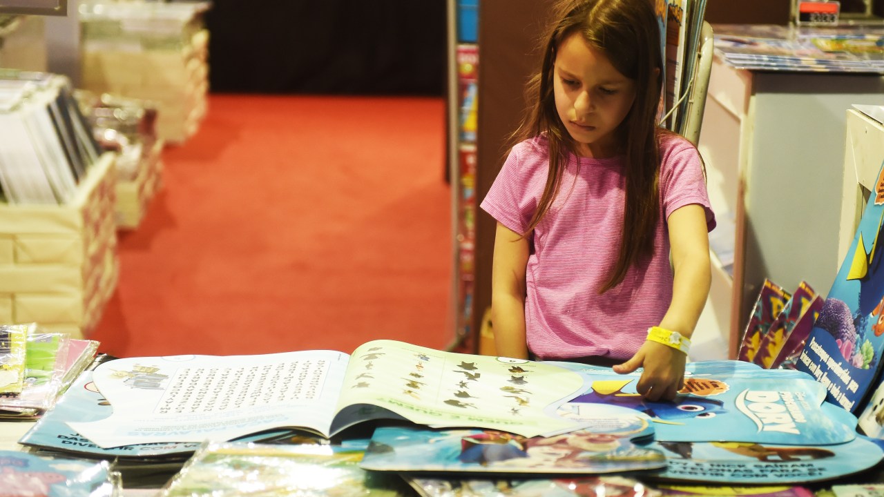 Menina observa observa estande de livros infantis durante a 24ª Bienal de Livros no Pavilhão Anhembi em São Paulo
