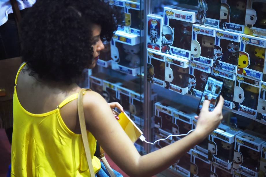 Garota fotografa bonecos a venda em estande da 24ª Bienal de Livros, em São Paulo - 30/08/2016