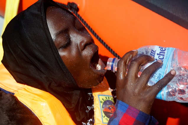 Uma imigrante se hidrata após ser resgatada pela organização espanhola Proactiva, resgata um imigrante da Somália, ao largo da costa da Líbia no mar Mediterrâneo