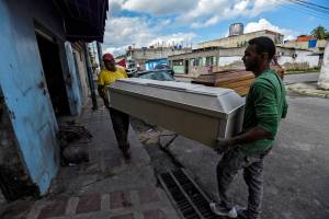 Trabalhadores carregam um caixão de MDF em Maracay, na Venezuela