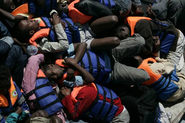 Imigrantes ilegais resgatados pela Marinha de Malta dormem no convés de uma embarcação militar
