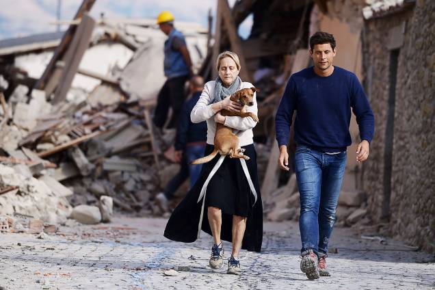 Mulher carrega cão nos braços em meio aos prédios destruídos na cidade italiana de Amatrice, após forte terremoto atingir a região - 24/08/2016