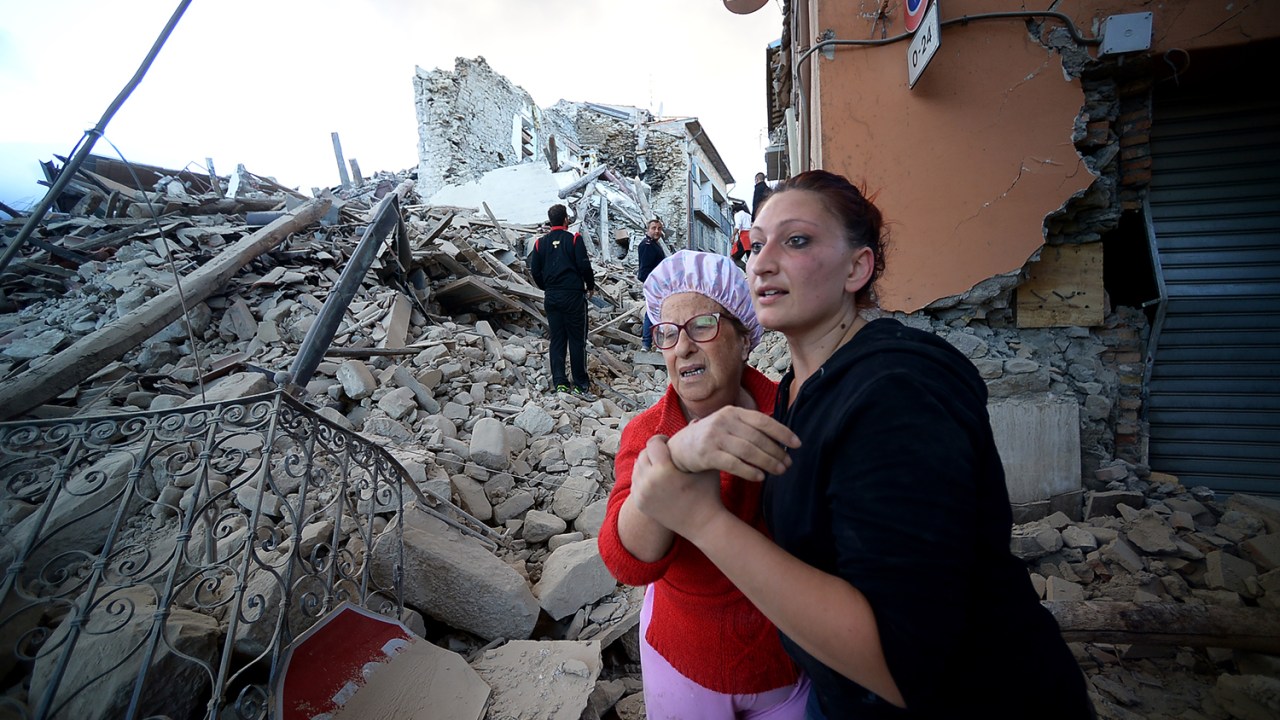 Moradores caminham entre os escombros de prédios, após forte terremoto atingir a região de Amatrice, na Itália - 24/08/2016
