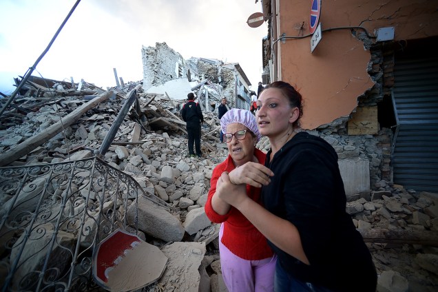 Moradores caminham entre os escombros de prédios, após forte terremoto atingir a região de Amatrice, na Itália - 24/08/2016