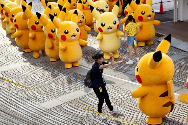 Mulher indica caminho para ator vestido do monstrinho Pikachu, em um desfile no centro de Yokohama, no Japão