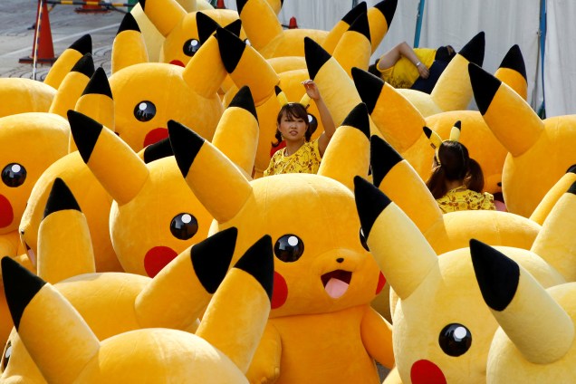 Mulher indica caminho para atores vestidos do monstrinho Pikachu, em um desfile no centro de Yokohama, no Japão
