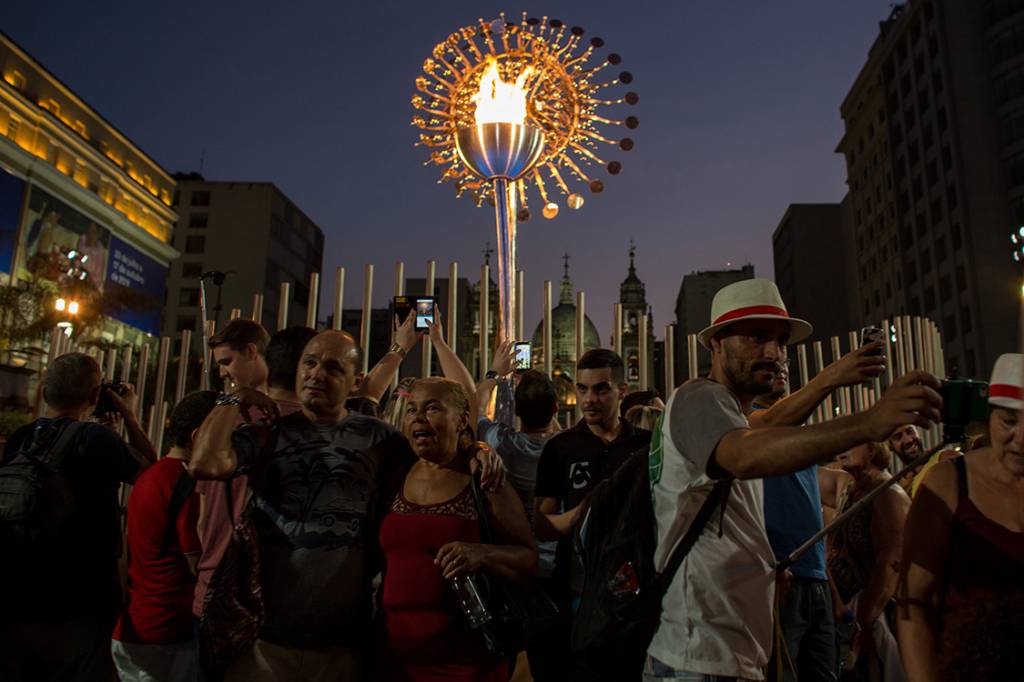 Turistas tiram fotos em frente a pira olímpica próxima a Igreja da Candelaria