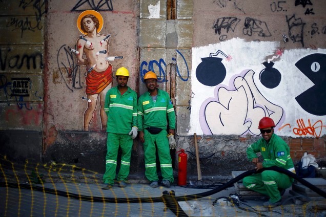 Trabalhadores posam para fotógrafo em frente a uma parede grafitada no Rio de Janeiro