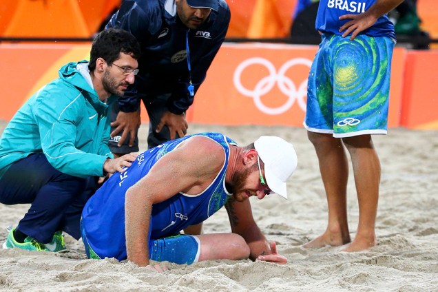 Alison Schmidt recebe atenção dos fisioterapeutas após sofrer lesão em jogo contra a Itália, na modalidade de vôlei de praia