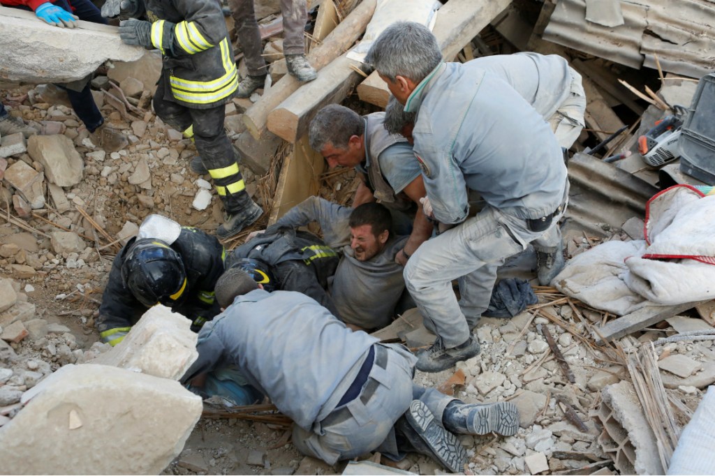 Bombeiros e civis resgatam um homem em Amatrice, na Itália