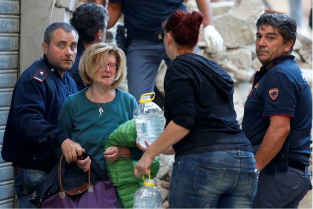 Socorristas auxiliam uma mulher resgatada em Amatrice, na Itália, após forte terremoto atingir a região - 24/08/2016