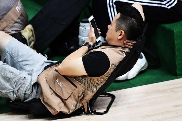 Fotógrafo descansa durante intervalo do jogo de basquete entre Estados Unidos e China