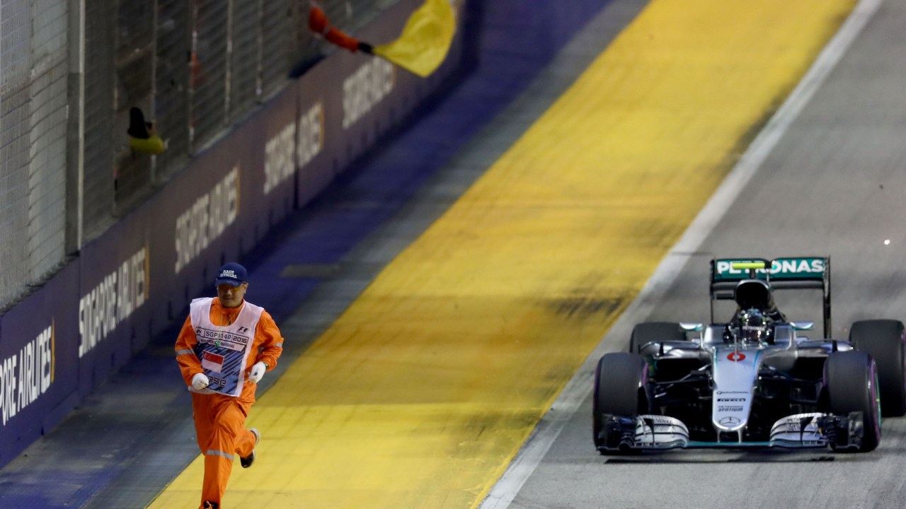 O piloto alemão Nico Rosberg passa perto de um fiscal de prova durante o Grande Prêmio de Singapura