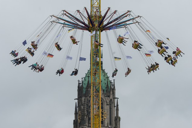Visitantes brincam em uma atração do parque de diversões em frente da igreja "Paulskirche" (São Paulo) durante a Oktoberfest em Munique, na Alemanha