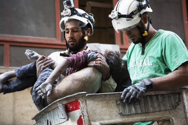 Bombeiros retiram o corpo de uma menina do meio dos destroços de um prédio, após um bombardeio no bairro de Al-Shaar em Alepo, na Síria - 27-09-2016