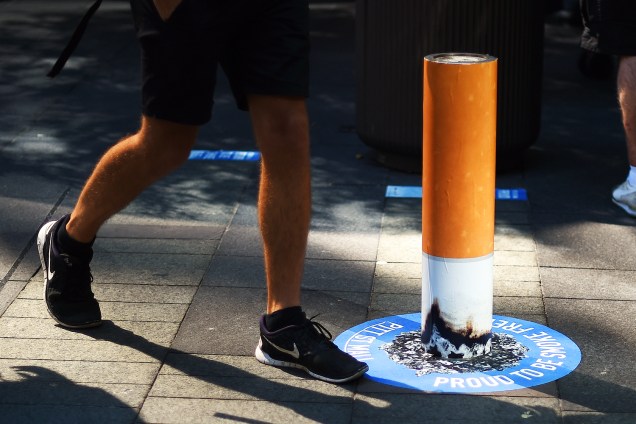 Pedestre caminha próximo a um poste de amarração pintado com as cores de um cigarro, em campanha antifumo realizada na cidade de Sydney, na Austrália - 26/09/2016