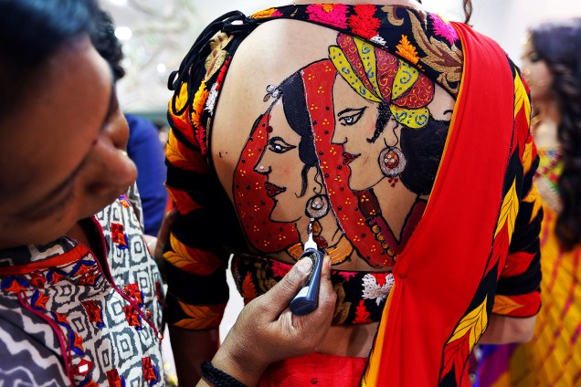 Artista desenha nas costas de uma garota em preparação para festival religioso, na Índia - 26-09-2016