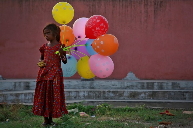Garota vende balões, próximo ao rio Yamuna, durante festival religioso indiano em homenagem ao lorde Ganesha - 15/09/2016