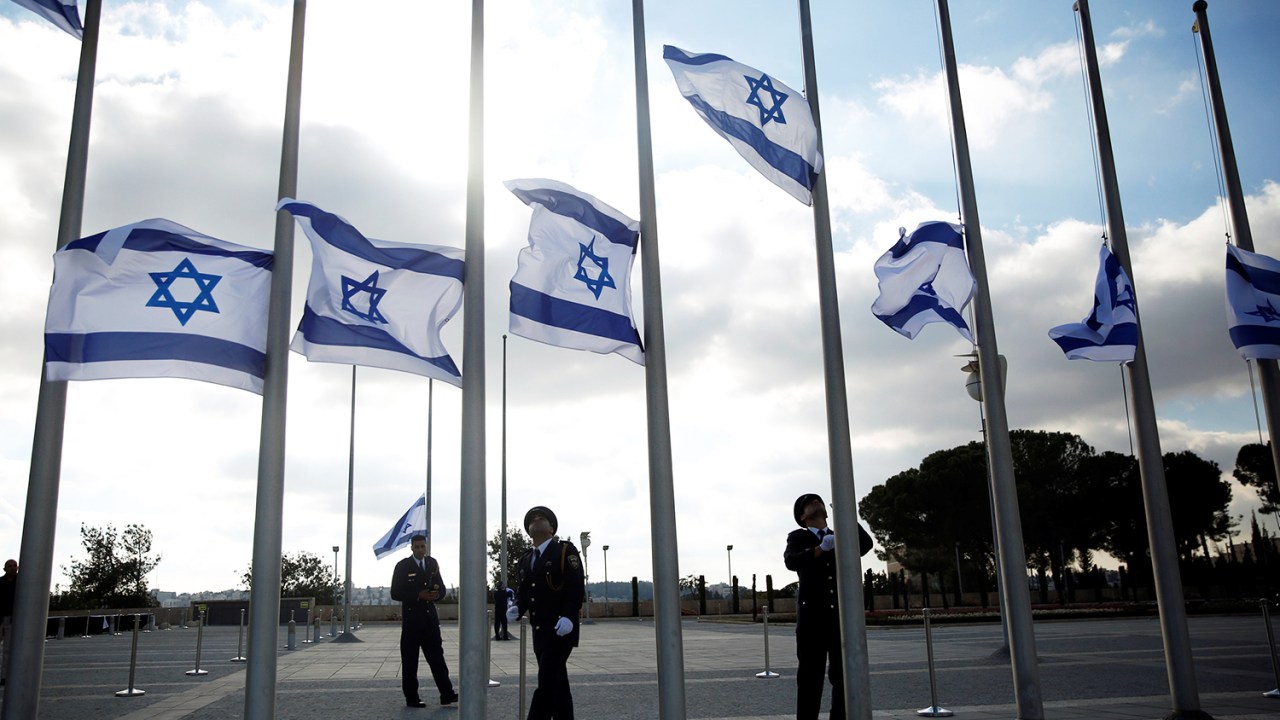 Guardas presidenciais colocam bandeiras a meio-mastro em sinal de luto pela morte do ex-presidente de Israel, Shimon Peres, em frente ao parlamento do país, na cidade de Jerusalém - 28/09/2016