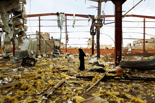 Mulher observa fábrica destruída após ataques aéreos ocorrerem em Saná, no Iêmen - 15/09/2016