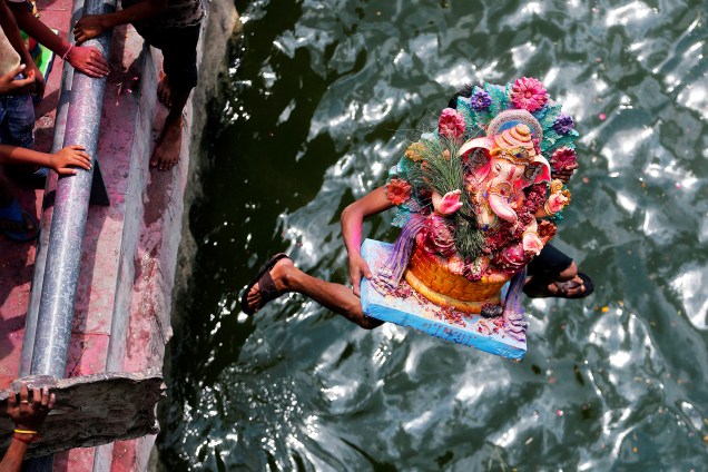 Homem pula no rio Sabarmati carregando imagem do deus Ganesha, durante festival em Ahmedabad, na Índia - 15/09/2016