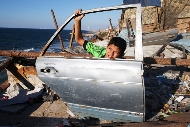 Garoto palestino segura porta de carro encontrada em praia próxima à Cidade de Gaza - 28/09/2016