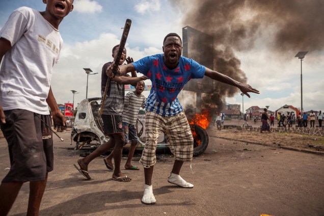 Manifestantes se reúnem em frente a um carro em chamas durante protesto contra a reeleição do presidente Joseph Kabila, no poder desde 2001, em Kinshasa, na República Democrática do Congo - 19/09/2016