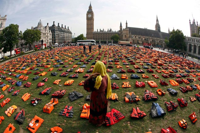 A curadora Rehab Sidiqi, posa para uma fotografia entre 2500 coletes usados por refugiados durante a travessia da Turquia para a ilha grega de Chois em uma instalação na Praça do Parlamento no centro de Londres, na Inglaterra - 19/09/2016