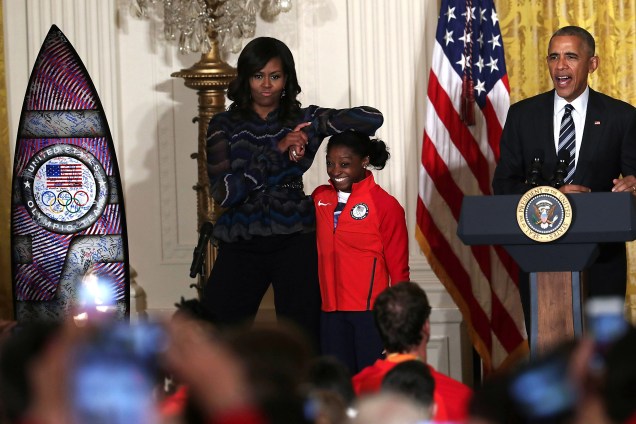 A primeira-dama dos Estados Unidos, Michelle Obama brinca com a ginasta Simone Biles enquanto o presidente Barack Obama discursa durante evento para atletas olímpicos na Casa Branca, em Washington - 29/09/2016