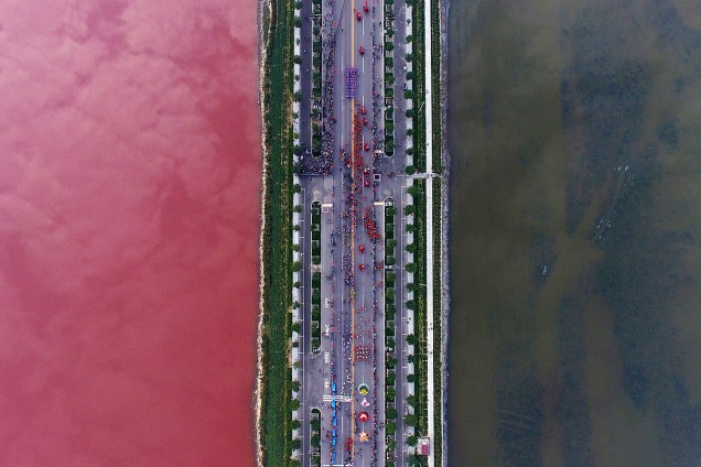 Imagem aérea mostra lago separado por rodovia em Yuncheng, na China, tem cor da água alterada pela presença de algas - 27-09-2016