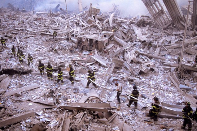 Bombeiros carregam mangueira entre as ruínas do World Trade Center