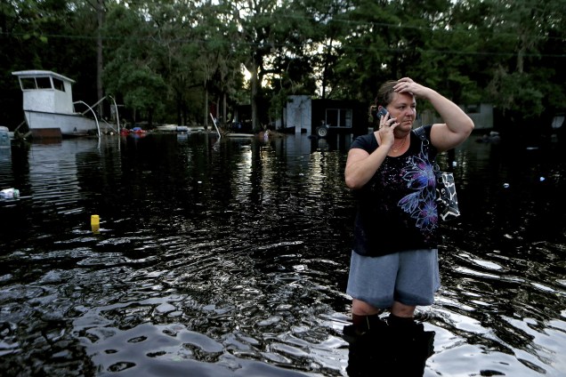 Mulher fala ao telefone em meio a uma rua inundada após tempestade associada ao furacão Hermine em Tampa, na Flórida - 02/09/2016