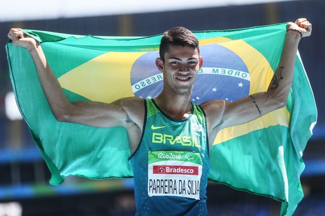 Rodrigo Parreira carrega a bandeira brasileira após conquistar a prata no salto em distância masculino na categoria T36 (problemas neuromotores)