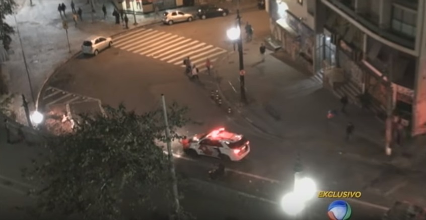 Rapaz de camiseta vermelha é atingido no quadril pelo carro da Polícia Militar