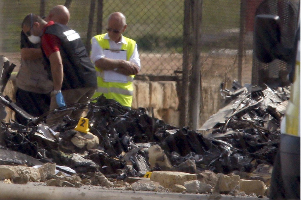 Funcionários inspecionam os destroços do avião que explodiu no ar, em Malta