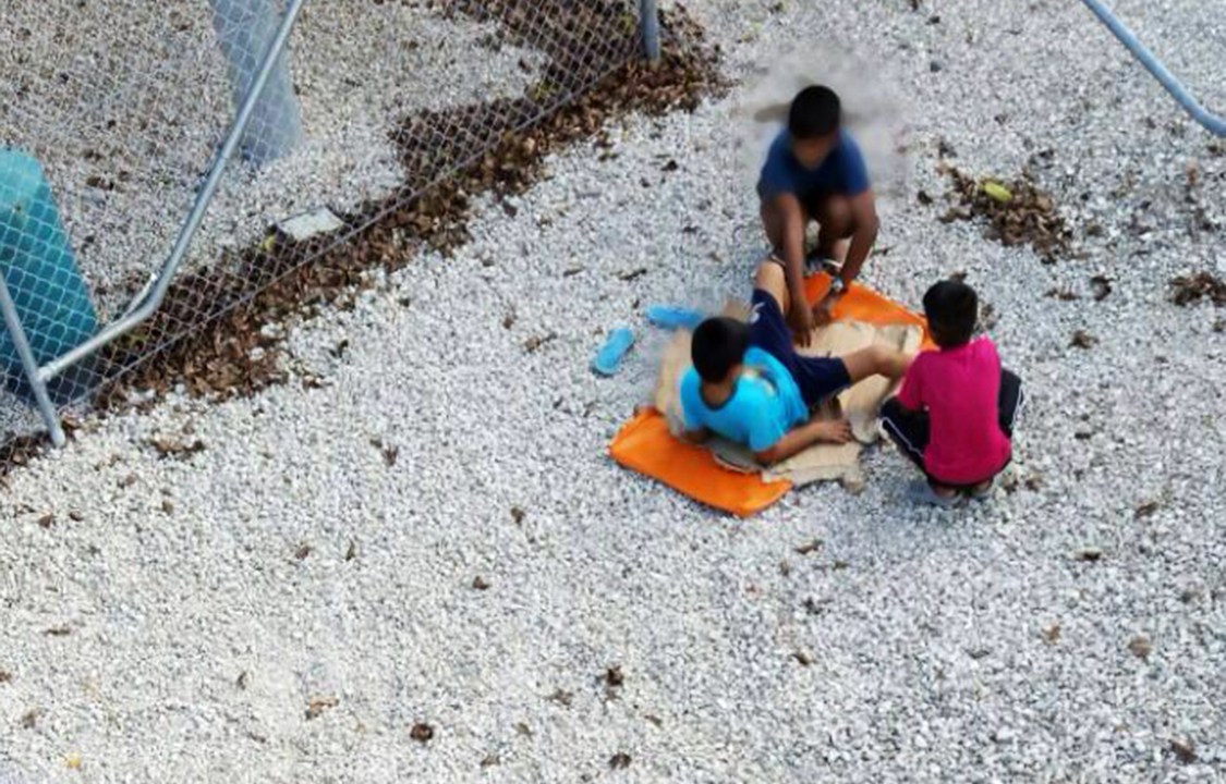Crianças brincam perto das grades de um centro para refugiados na Austrália